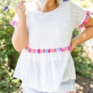 White crocheted blouse with colorful tassels.
